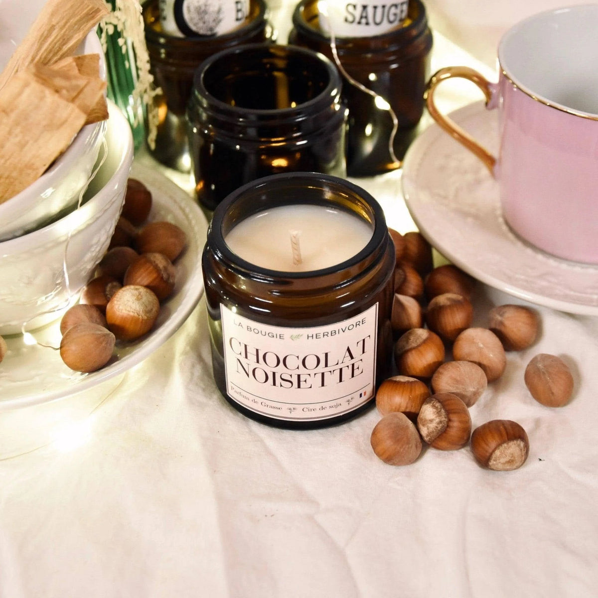 Bougie chocolat noisettes de La Bougie Herbivore dans un ambiant chaleureux avec des noisettes