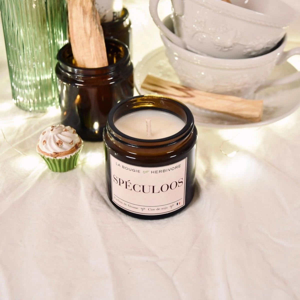 Bougie parfumée spéculoos dans un pot en verre, avec des éléments décoratifs en arrière-plan
