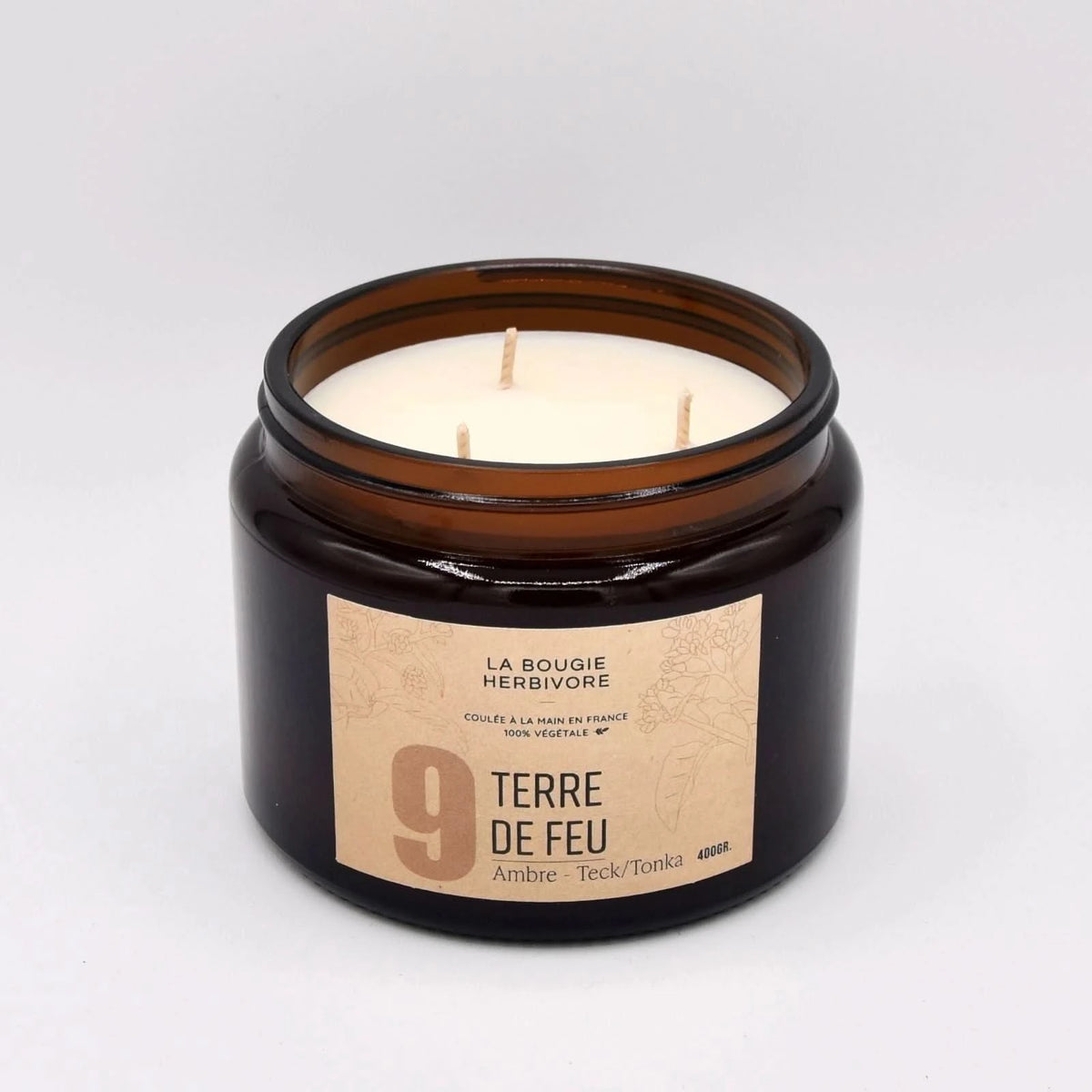 Bougie parfumée ambre teck dans un pot en verre marron avec trois mèches et étiquette élégante