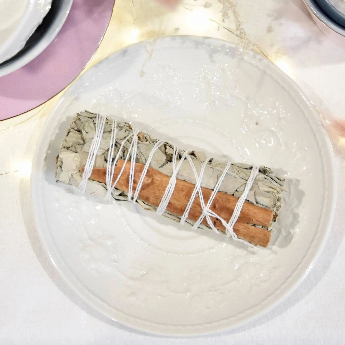 Fagot sauge blanche cannelle de La Bougie Herbivore sur une assiette blanche décorative