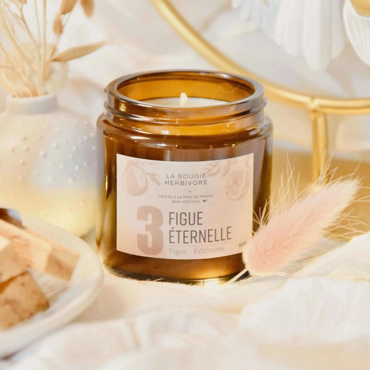 Bougie parfumée figue dans un pot en verre avec étiquette décorative et éléments naturels environnants