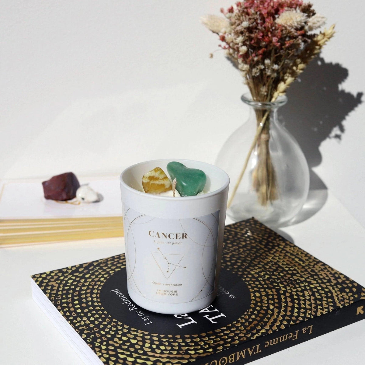 Bougie signe astrologique Cancer avec pierres naturelles et design élégant sur un livre